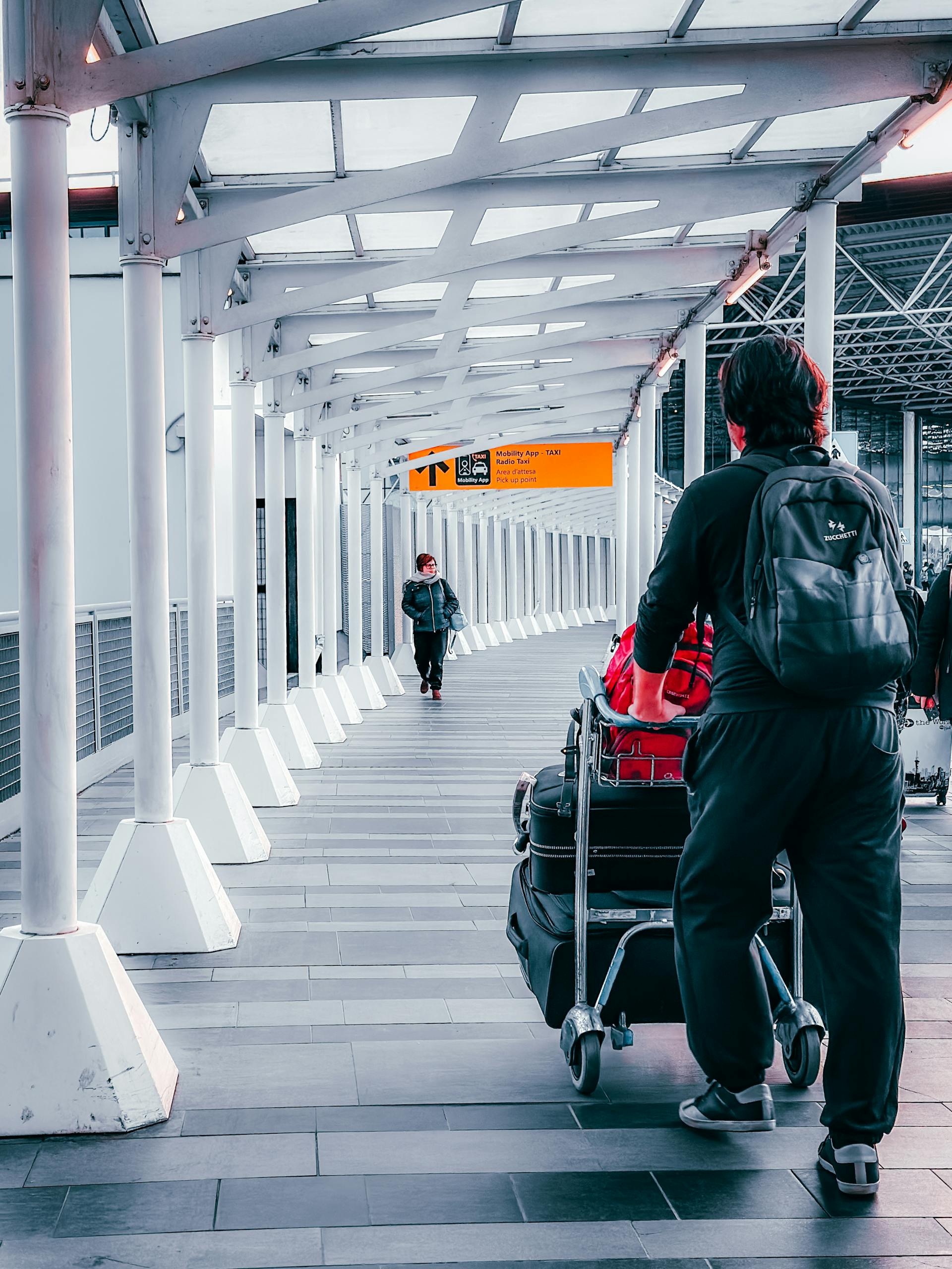 Travelers with luggage trolleys navigating through Dortmund Airport's terminal walkway.